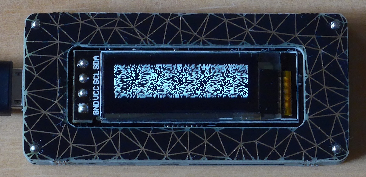A circuit board with an 128 × 32 OLED screen mounted in the centre. The screen shows a random pattern of lit and unlit pixels.