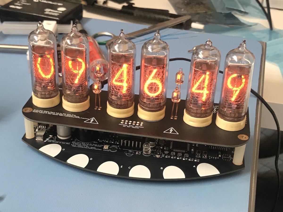 A working nixie tube clock on a messy desk